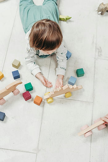 baby playing, colored blocks, child playing, colorful wooden toys, light floor, fun educational setting, wooden blocks, educational toys, toddler play, indoor play, colorful blocks