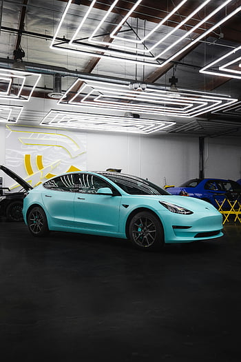 Blue Tesla, electric car, sleek design, indoor garage, geometric lighting, stylish setting, modern vehicle, luxury car, automotive showcase, car display, electric vehicle