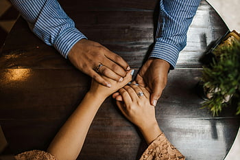 pár drží za ruce, dřevěný stůl, milovat, spojení, zásnubní prsteny, romantické gesto, intimní okamžik, ruku v ruce, milující pár, vztah, jednotnost