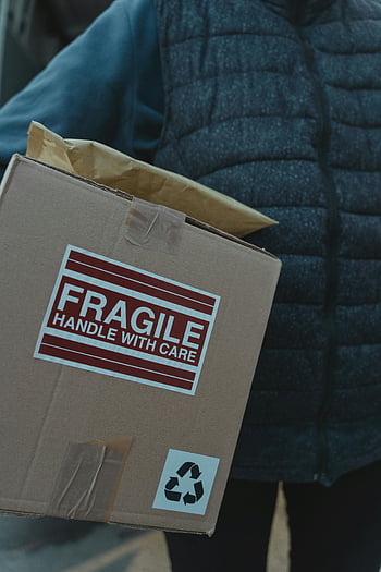 package delivery, fragile package, handle with care, close-up photo, person delivering, care labels, cardboard box, shipping, delivery service, package handling, recycling symbol