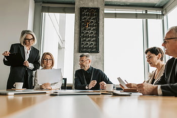 business professionals, discussing documents, modern meeting room, group discussion, office environment, professional meeting, business meeting, document review, collaborative work, workplace interaction, corporate setting