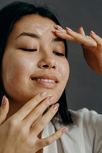 wanita Asia, krim wajah, rutinitas perawatan kulit, tersenyum, latar belakang abu-abu, mengaplikasikan krim, keindahan, perawatan kulit, perawatan wajah, cantik alami, perawatan diri