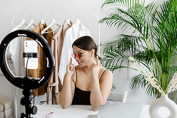 vlogging, ring light, stylish woman, fashion accessories, greenery, sunglasses, video recording, fashion vlog, indoor setting, casual style, modern decor