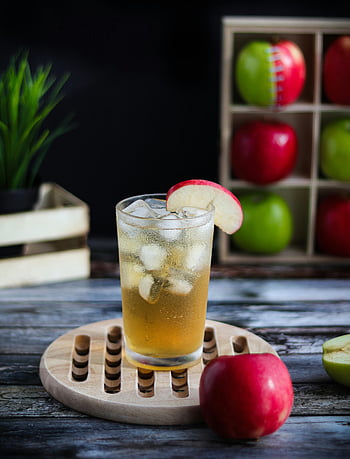 apple juice, ice cubes, fresh apples, rustic wooden table, chilled glass, apple slice, wooden coaster, red apples, green apples, drink photography, healthy beverage