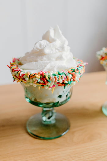 ice cream sundae, whipped cream, rainbow sprinkles, glass dish, colorful sprinkles, dessert, sweet treat, whipped topping, ice cream bowl, festive dessert, creamy dessert