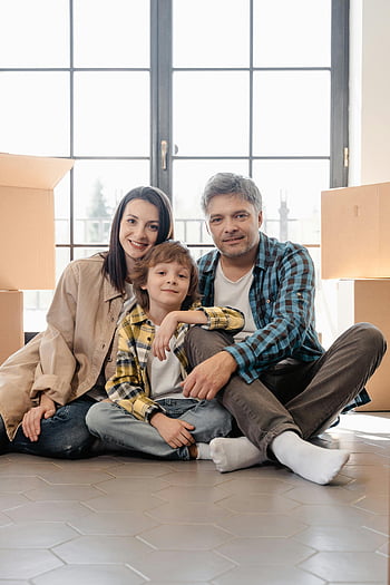 Familie, Umzugstag, fröhliche Familie, auf dem Boden sitzen, umgeben von Kisten, Familienfoto, neues Zuhause, Umzugskartons, Familienporträt, Familienmoment, einziehen