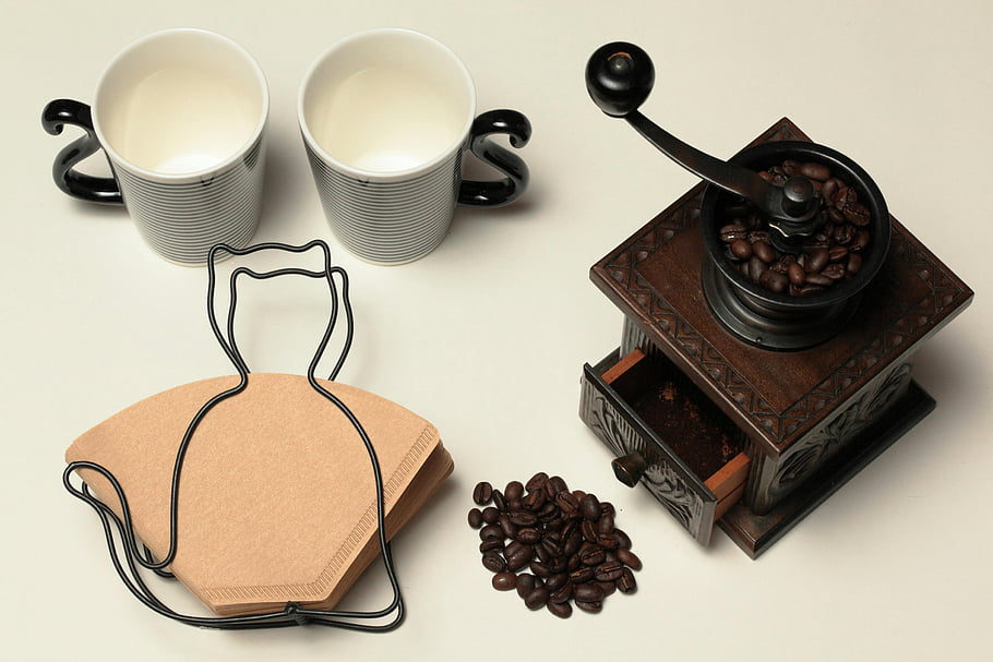 vintage brown coffee grinder, white surface, coffee beans, coffee cups, coffee filters, retro coffee grinder, coffee accessories, coffee preparation, coffee brewing, coffee equipment, coffee beans grinder