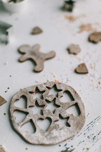 cookie shapes, shallow focus photography, gingerbread dough, festive cookie cutouts, Christmas baking, gingerbread man, heart shapes, snowflake shapes, baking preparation, holiday treats, festive baking