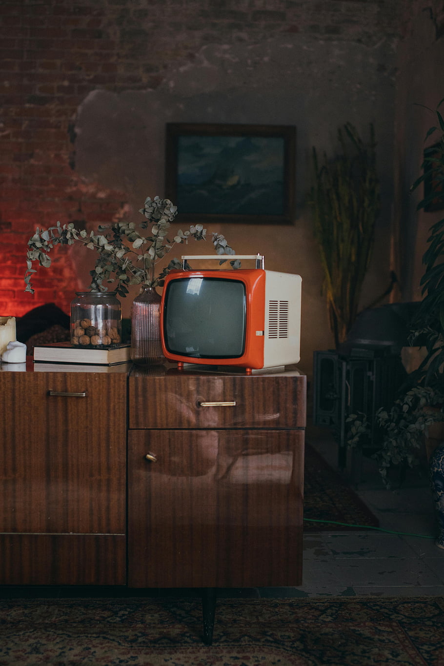 Oranžová vintage televize, hnědá dřevěná skříňka, retro vibe, Klasická televize, Nostalgická výzdoba, Nábytek z poloviny století, Vintage elektronika, retro interiér, Oranžová televize, dřevěný nábytek, prastarý styl