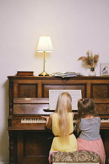 Børn, der spiller klaver, unge piger, musikalsk læring, Hyggelige indendørs indstilling, klaver lektion, nodeblad, vintage piano, lampe, indendørs indretning, musik uddannelse, to børn