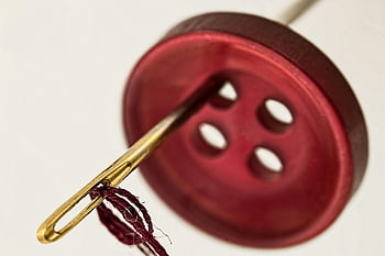 brass needle, red cloth button, macro photograph, needle threading, red thread, brown button, sewing, close-up, textile, craft, needlework