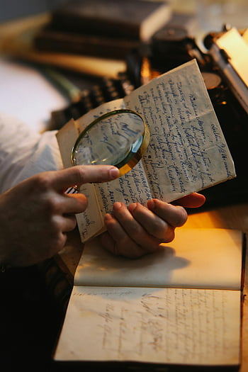 hands holding paper, handwritten letter, magnifying glass, close-up shot, examining text, vintage document, antique paper, detailed inspection, historical document, old letter, close-up hands