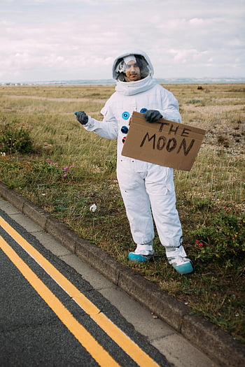 astronaut, hitchhiking, space suit, roadside, sign, the moon, field, person, costume, outdoor, travel