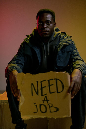 homeless man, Need a Job sign, unemployment, poverty, cardboard sign, indoor setting, jobless, economic hardship, social issues, struggling individual, homelessness awareness