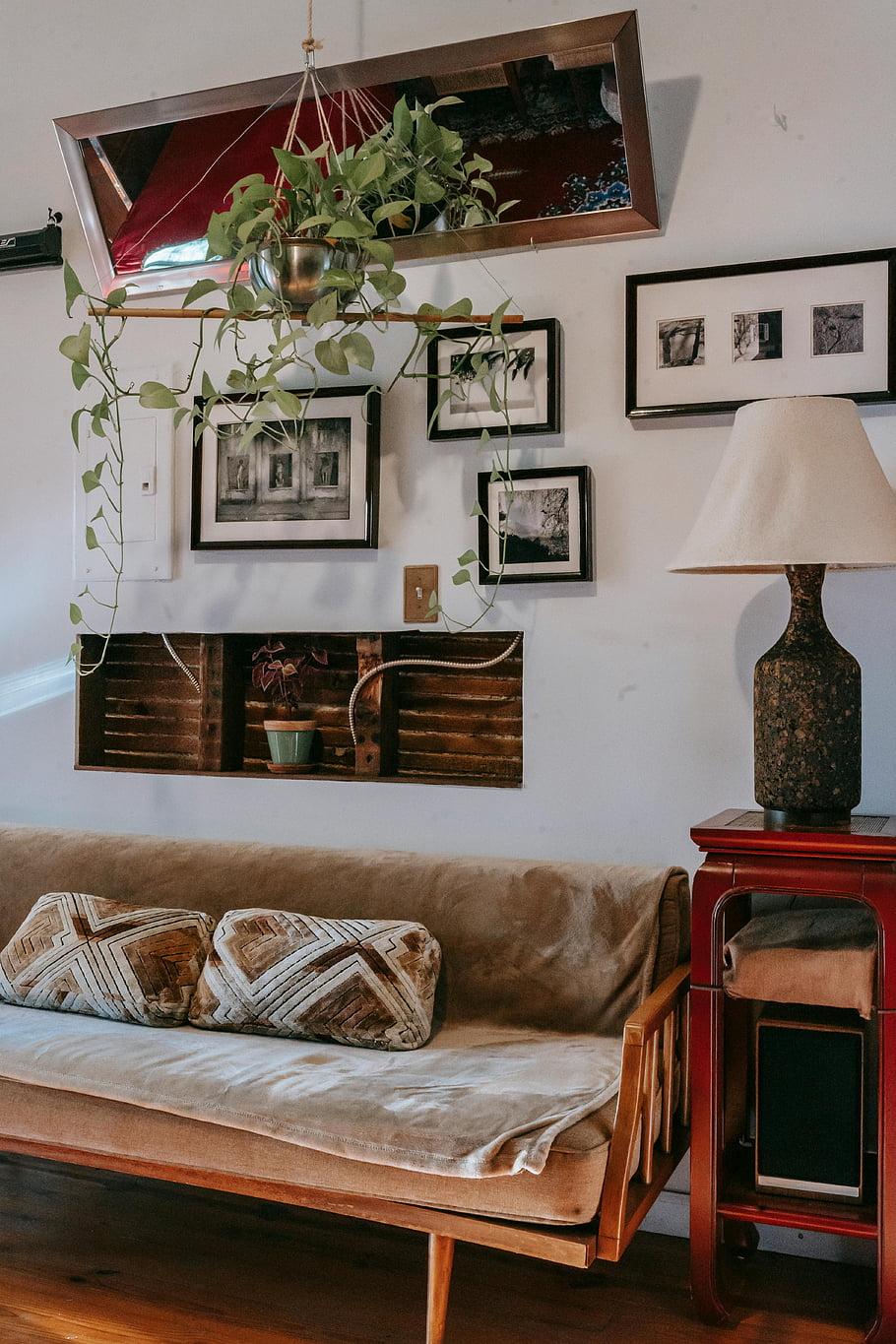 útulný obývací pokoj, vinobraní výzdoba, rustikální prvky, pohodlná pohovka, zarámované obrázky, Elegantní lampa, malá zobrazovací skříň, výzdoba stěn, závěsné rostliny, domácí interiér, Útulná atmosféra