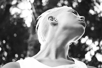 foto in scala di grigi, ritratto in bianco e nero, giovane donna, capelli corti, guardando in alto, fotografia artistica, Immagine monocromatica, soggetto femminile, ambientazione esterna, luce naturale, espressione sincera