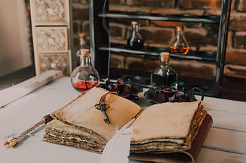 old book, candles, wooden table, glass bottles, vintage setting, potion bottles, mystical vibe, antique books, rustic decor, alchemy, magic
