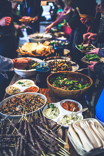 étalage du buffet, salades, brochettes, trempettes, rassemblement intérieur, nourriture vibrante, table de déjeuner, événement animé, table en bois, salle à manger commune, Options saines