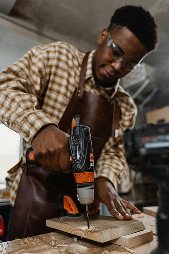 perforazione dell'uomo, tavola di legno, trapano elettrico, negozio di lavorazione del legno, Artisan concentrato, artigianato, carpenteria, Fai da te, utensili, occhiali di sicurezza
