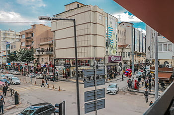 people walking on sidewalk, bustling city street, pedestrians, shops, vehicles, clear day, lively urban life, cityscape, street scene, urban environment, daytime city