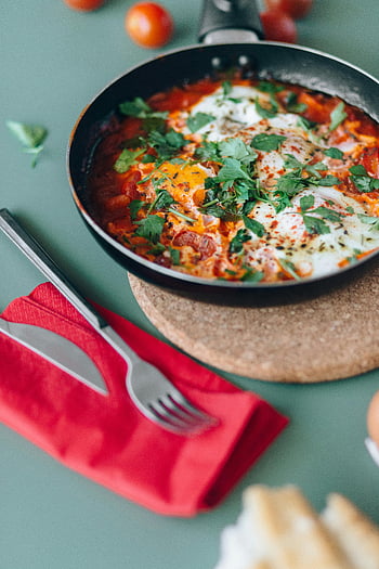 shakshuka, pan, eggs, tomatoes, fresh herbs, savory dish, breakfast, brunch, Middle Eastern cuisine, red napkin, fork and knife