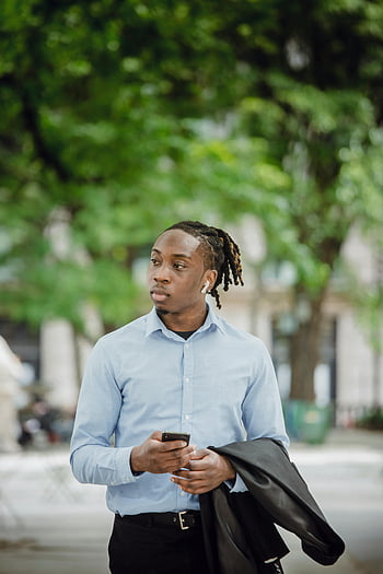selbstbewusster Manager, Smartphone, Park, brechen, kabellose Ohrhörer, SMS, junger Mann, Outdoor-Einstellung, Professionelle Kleidung, lässiger Moment, technologische Nutzung