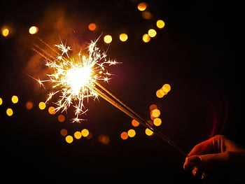 sterretje, Verlichte vuurwerk, levendig sterretje, donkere achtergrond, bokeh lichten, viering, gloeiend sterretje, nacht scene, feestelijke lichten, Hand vasthoudend schittering, sprankelend effect