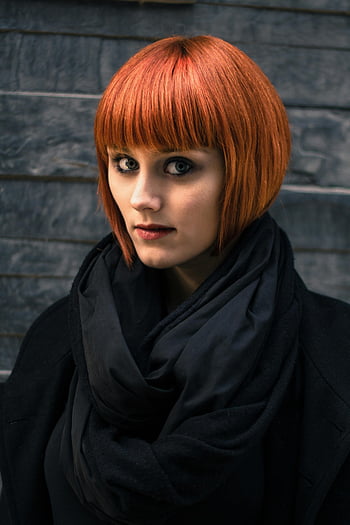 rothaarige Frau, schwarzer Mantel, dunkler Schal, strukturierte Wand, stilvolle Pose, elegantes Aussehen, Rote Haare, schwarzes Outfit, Portraitfotografie, Mode-Porträt, urbaner Stil