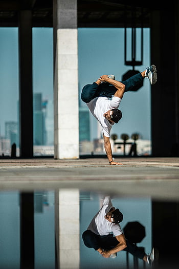 breakdancing, man in white shirt, handstand, cityscape background, street performance, skilled dancer, urban dance, reflection, outdoor dance, breakdance move, city life