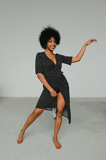 žena, černé a bílé puntíky šaty, šedá podlaha, Veselá černá žena, tančí v interiéru, afro vlasy, styl, Vnitřní tanec, polka dot šaty, Černá žena, Afro styl