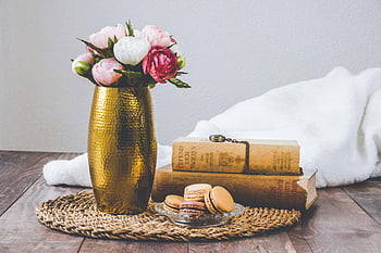 golden vase, assorted flowers, rustic still life, macarons, vintage books, wooden table, floral arrangement, decorative vase, antique books, macaron dessert, cozy setting