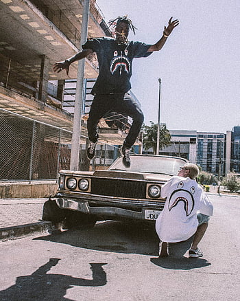 man springen, Voorzijde van de auto, bruine auto, stedelijke omgeving, streetwear mode, vintage auto, Street Style, actie foto, buitenfotografie, dynamische pose, stadsgezicht achtergrond