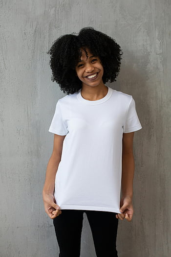 munter sort kvinde, hvid t-shirt, afro hår, betonvæg, studio portræt, smilende kvinde, Casual outfit, indendørs fotografering, naturlige skønhed, etnisk mode, studio shoot