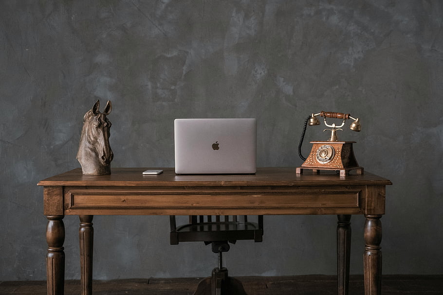 vinobraní pracoviště, laptop, chytrý telefon, rotační telefon, socha koně, dřevěný stůl, Elegantní pracovní prostor, vinobraní interiér, kancelářská výzdoba, Rustikální stůl, moderní technologie