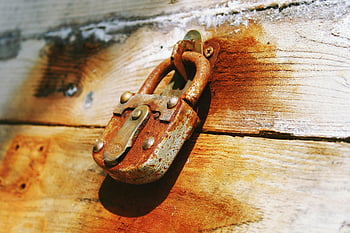 hnědý visací zámek, Rustikální visací zámek, Zrezivělý visací zámek, zvětralé dřevěné dveře, Detailní zámek, Symbol ochrany, Bezpečnostní symbol, starý visací zámek, Vintage visací zámek, Dřevěný zámek dveří, rezavý zámek