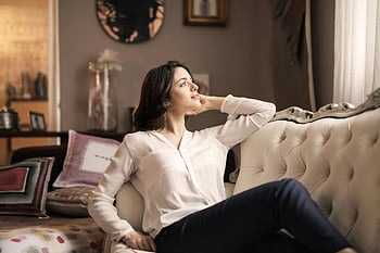 woman in white dress shirt, black pants, vintage sofa, serene reflection, well-designed interior, luxurious furniture, indoor setting, casual pose, elegant style, home decor, comfortable living room