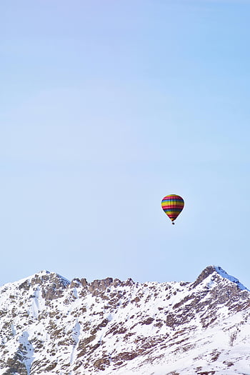 hot air balloon, snow covered mountain, clear blue sky, colorful balloon, majestic mountains, winter landscape, aerial view, mountain peaks, scenic view, outdoor adventure, nature photography