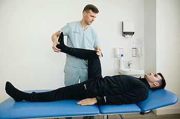 physiotherapist, patient, leg stretching exercises, treatment table, physical therapy, rehabilitation, healthcare, medical professional, exercise assistance, recovery, clinic setting
