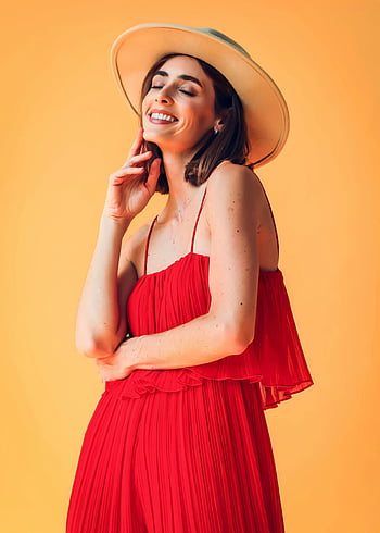 femme en robe rouge, robe rouge, chapeau, femme élégante, fond orange, portrait en studio, pose confiante, photographie de mode, tenue rouge, femme au chapeau, prise de vue en studio