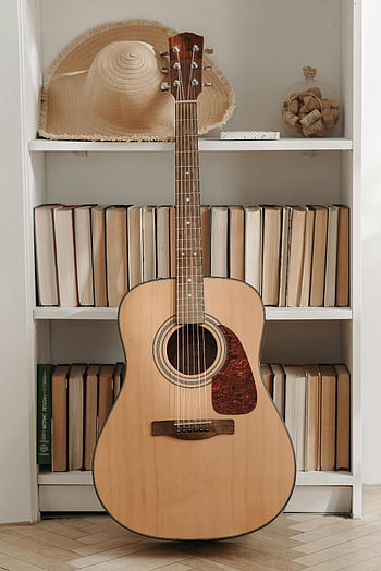 brązowa gitara akustyczna, półka na książki, książki, słomiany kapelusz, Przytulna biblioteka, atmosfera, drewniana gitara, instrument akustyczny, wystrój domu, pokój muzyczny, zabytkowe książki