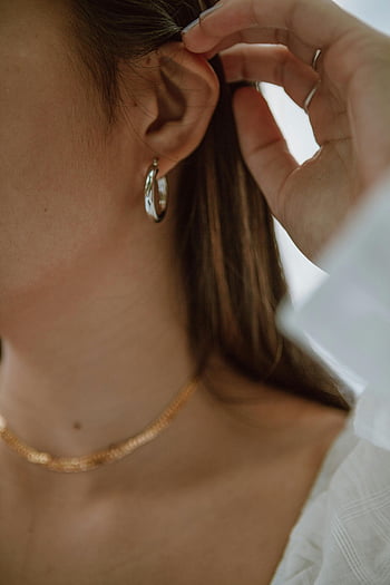 Kvinde rører ved hår, hvid baggrund, nærbillede skudt, elegante smykker, mode, minimalisme, øre, halskæde, hoop øreringe, hånd, hvid bluse