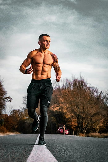 Nackter Oberkörper Mann, Joggen, Fitness, Outdoor -Übung, Herbstlaub, schwarze, kurze Hosen, Gehweg, Laufen, sportlich, gesunder Lebensstil, Straßentraining