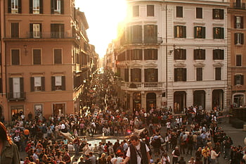 people gathering, sunset, historic Roman street, bustling crowd, vibrant urban atmosphere, cityscape, evening scene, public space, urban life, street scene, sunset crowd