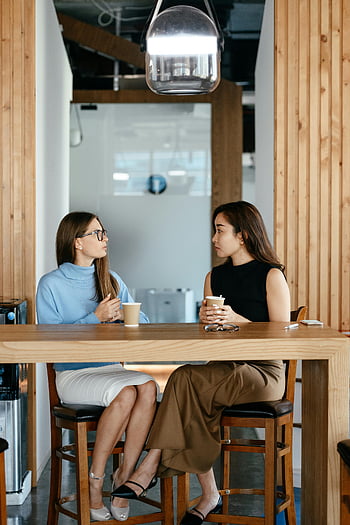 Multietniske forretningskvinder, kaffepause, Moderne café, Professionelle kvinder, forskellig samtale, Jobdiskussion, afslappet møde, forretningsmøde, kaffebar, Professionel påklædning, Moderne omgivelser