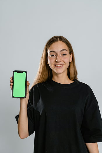 žena, tričko s černou posádkou, držení smartphone, Teal iPhone pouzdro, Usmívající se teenager, zelená obrazovka, maketa, telefonu, Neformální outfit, studio shot, technologie