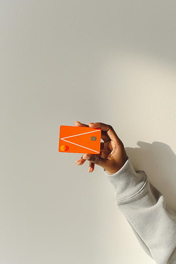 carte de maintien à la main, carte de débit orange vif, main grossier, fond clair, carte de crédit, mode de paiement, transaction financière, carte en plastique, Finance moderne, titulaire de la carte, carte orange