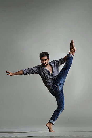 ballerino maschio, danza contemporanea, potenza e flessibilità, abbigliamento casual, Il piede sinistro sollevato, posa di ballo, girato in studio, espressione artistica, movimento dinamico, ballo a piedi nudi, fotografia in studio