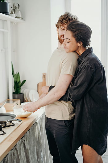امرأة تعانق الرجل،  زوجين شابين،  احتضان،  مطبخ مريح،  حب،  تاثير،  لحظة رومانسية،  زوجين في المطبخ،  المشهد الحميم،  حياة أليفة،  زوجان حنونان