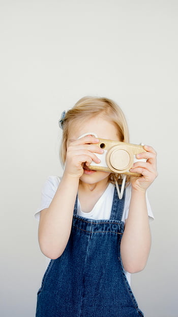 ragazza, scattare foto, macchina fotografica in legno, creatività giocosa, bel bimbo, salopette di jeans, giovane fotografo, fotografia per bambini, gioco creativo, giocattoli per bambini, attività divertenti