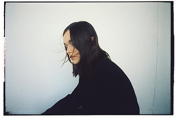 Frau in Schwarz, Langarm-Shirt, Stylisches Porträt, schwarzes Shirt, weißer Hintergrund, Haare weht, Modefotografie, Schwarz und weiß, weibliches Modell, Minimalistischer Stil, Portraitfotografie